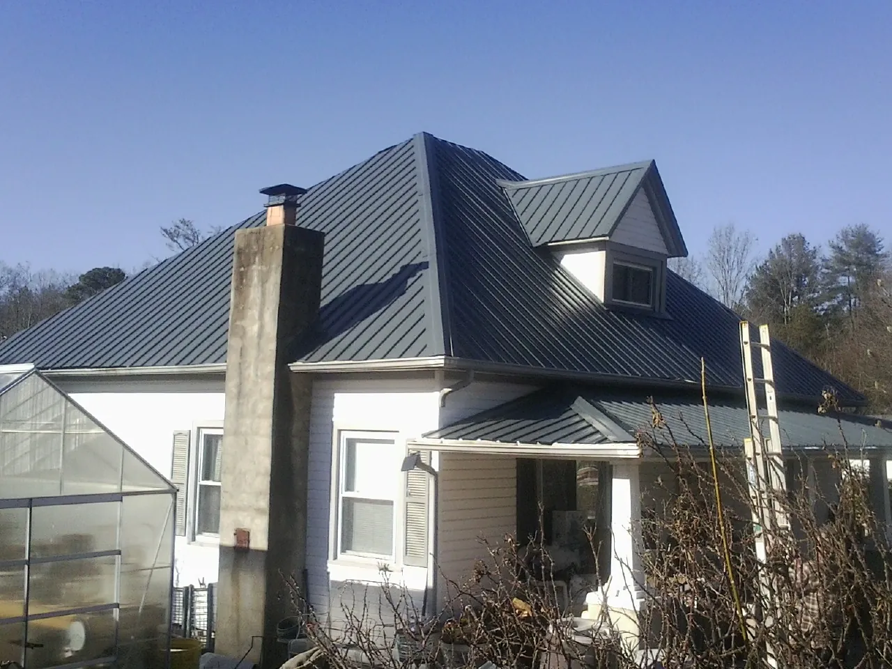 Dark blue standing seam metal roof on a white farmhouse with dormer — Slate & Tile Roof Repair by Roofing Brothers in Bushkill