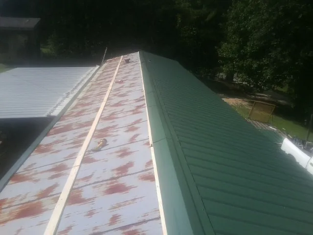 Old rusted panels beside newly installed green metal roofing — Wind Damage Roof Repair by Roofing Brothers in Bushkill