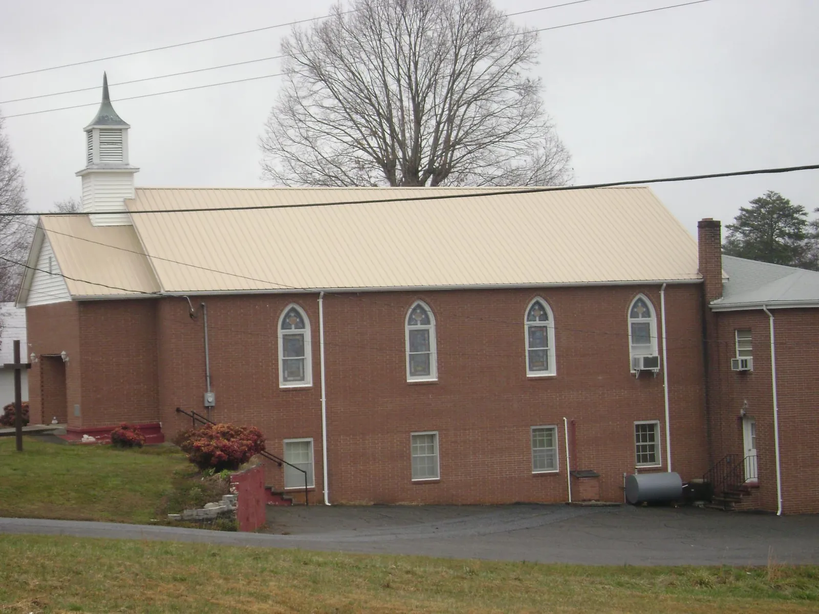 New tan metal roof on a brick church with a white steeple in Bushkill
