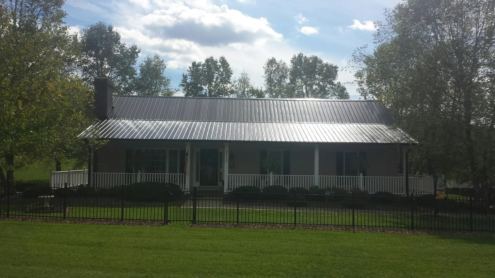 Gray metal roof on a brick ranch with a full width front porch — Gutter Guard Installation work by our crew in Bushkill