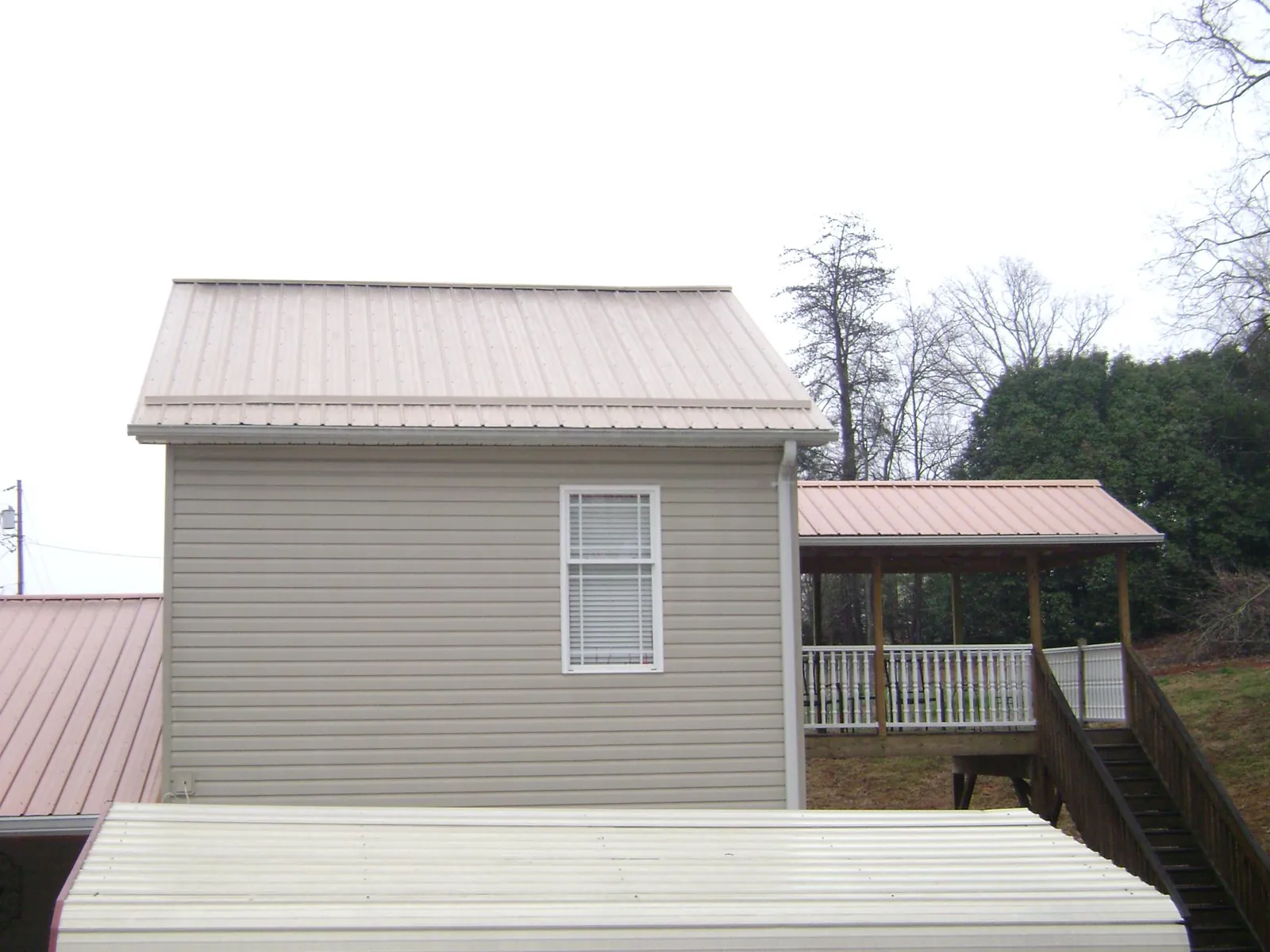 Tan metal roofs on a two story addition and attached porch, from a Roof Replacement job in Bushkill