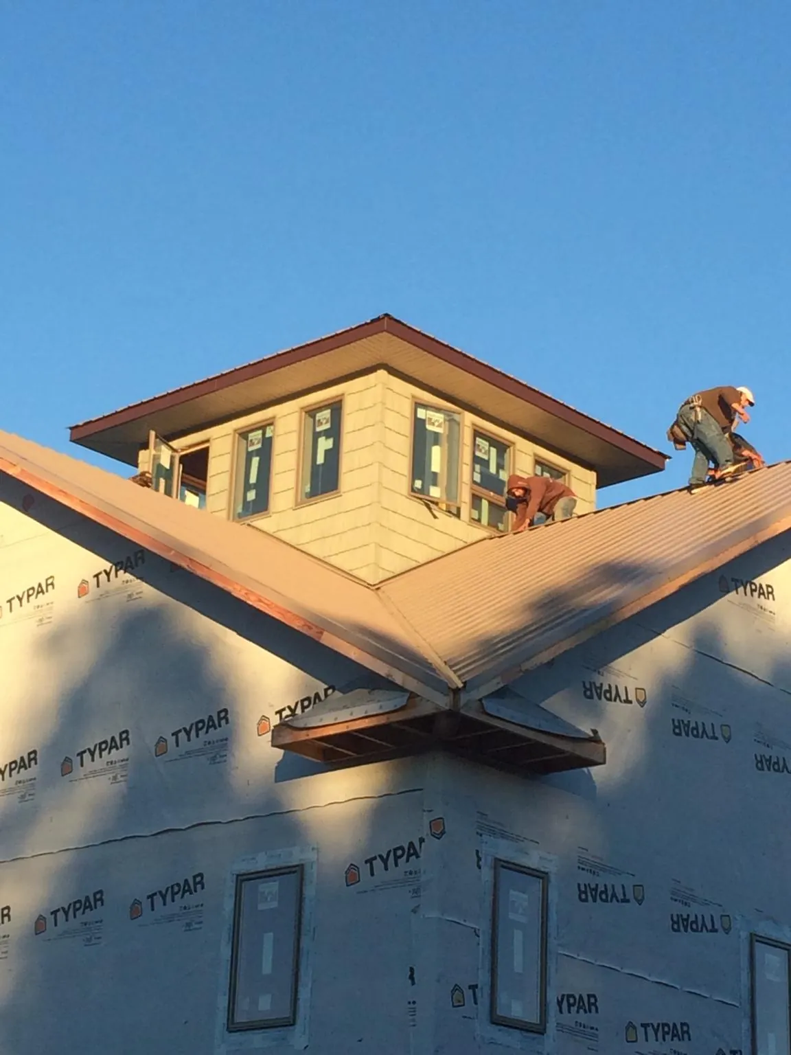 Roofers working around a rooftop cupola on a new metal roof at sunset — Roof Waterproofing in Bushkill by Roofing Brothers